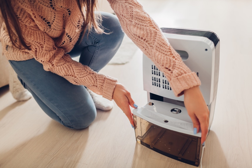 Women changing the water tank of a dehumidifier