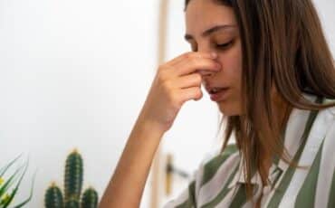 Woman pinching her nose to stop a nosebleed